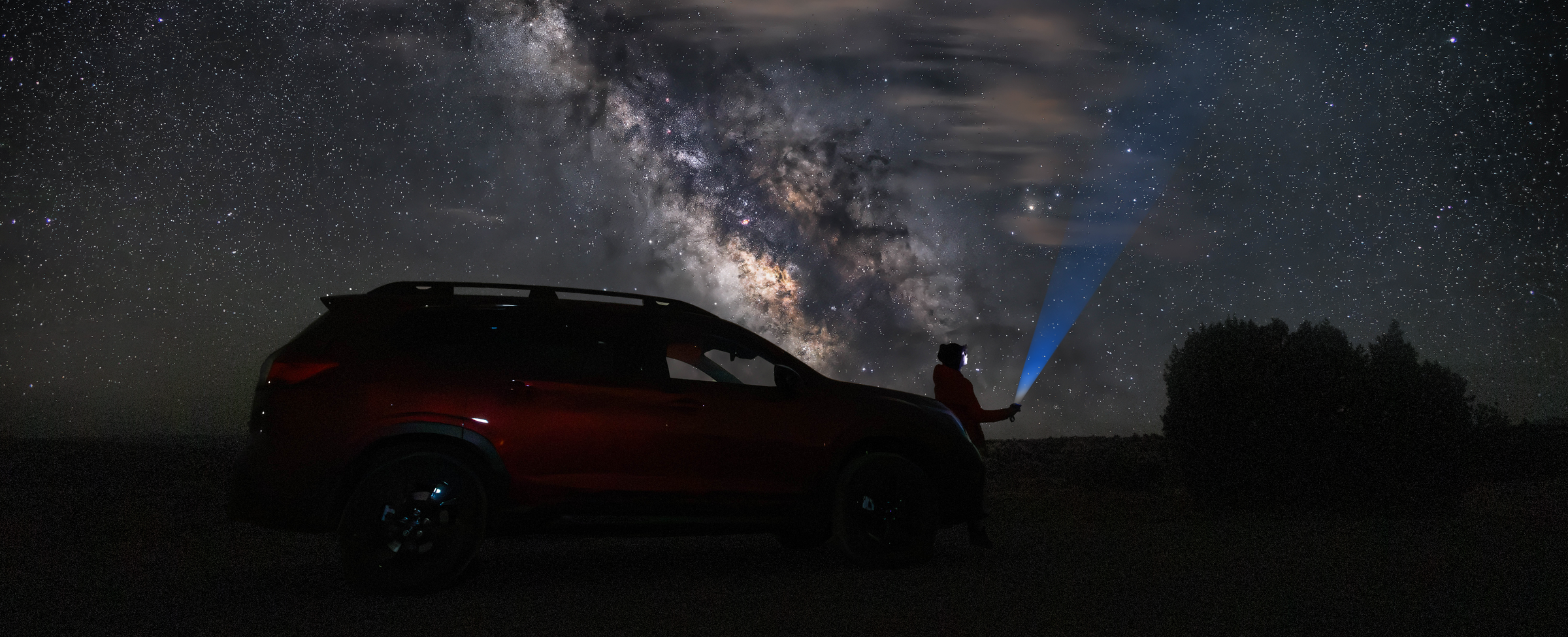 Photographer beside a red car beneath the Milky Way